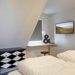 Schlafzimmer mit Doppelbett, schwarz-weißem Schrank und Wandfernseher.