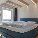 Schlafzimmer mit Doppelbett, Fenster und Holzdecke.