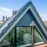 Dachgeschoss mit großem Fenster und Blick auf Nachbarhäuser.