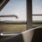 Durch das Fenster blickt man auf eine weite Landschaft mit Feldern und Bäumen.