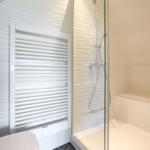 Dusche mit Glaswand und Heizkörper an der Wand