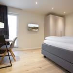 Schlafzimmer mit Bett, Schreibtisch und Kleiderschrank.