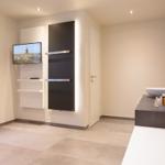 Moderne Dusche mit integriertem Fernseher und Waschtisch mit Keramikschale.