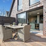 Terrasse mit Holzdecke und Sitzgruppe. Durchgang ins Haus mit Küchenbereich.