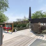 Terrasse mit Gartenmöbeln, Sonnenschirm und Holzdecke.