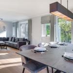 Esszimmer mit Tisch und Stühlen. Wohnbereich mit Sofa und Fenstern.