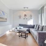Wohnzimmer mit grauem Sofa, Fernseher und drei Wandbildern.