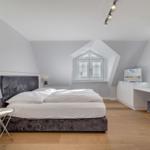 Schlafzimmer mit Dachschrägen, Bett, Schreibtisch und Kleiderschrank.