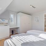 Schlafzimmer mit Bett, Kleiderschrank und TV. Durchgang zur Badewanne.