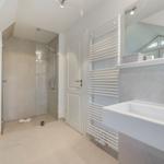 Badezimmer mit Dusche, Waschmaschine und Handtuchwärmer.