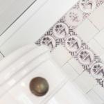 Badezimmer mit dekorativen Fliesen und weißer Wandverkleidung