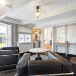 Wohnzimmer mit Ledersofa, Holzboden und Fenster zur Terrasse.