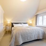 Schlafzimmer mit Bett, Nachttischen und Fenster