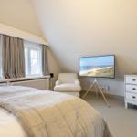 Schlafzimmer mit Bett, Fenster, Sessel, TV und Schrank.