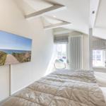 Schlafzimmer mit Dachschrägen, Bett, Fenster und Wandbild