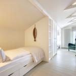 Schlafzimmer mit Bett, Kleiderschrank und Sitzgelegenheit