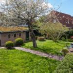 Garten mit Rasen, Weg und Sitzgelegenheit vor einem Haus mit Dachgarten.