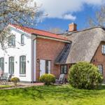 Haus mit strohgedecktem Dach und Garten mit Sitzgelegenheiten.