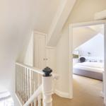 Staircase with view into bedroom with bed and wall art.