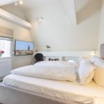 Bedroom with double bed, window, TV, and lamp.