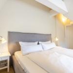 Bedroom with double bed, nightstand, and lamp under sloped ceiling.