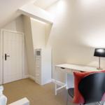 Bedroom with desk, chair, and cabinet under sloped ceiling.