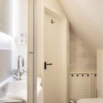 Bathroom with shower, sink, and toilet under sloped ceiling