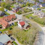 Aerial view of a residential area with houses, gardens, and roads.