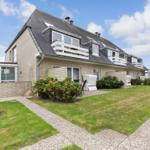 Holiday home with balconies and garden. Modern building with terrace and plants.