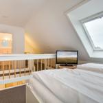 Bedroom with skylight, bed, and TV. View into adjacent room.