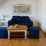 A living room with blue sofa, wooden table, and wall art.