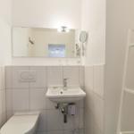 Bathroom with toilet, sink, and mirror on the wall.