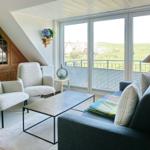 Wohnzimmer mit Sofa, zwei Sesseln und Blick auf Balkon.