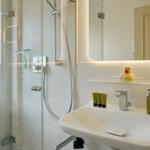 Bad mit Dusche, Waschbecken und Spiegel mit Beleuchtung.