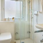 Bad mit Dusche, Waschbecken und Toilette. Fenster mit getöntem Glas.
