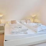 Schlafzimmer mit Doppelbett, zwei Nachttischen und Lampen.