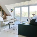 Wohnzimmer mit Sofa, Sesseln und Balkonansicht
