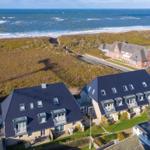Modernes Ferienhaus mit Blick auf das Meer und grünen Hügeln.