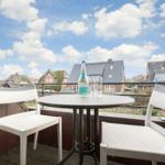 Terrasse mit Tisch und zwei Stühlen. Blick auf Dächer und Himmel.