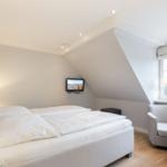 Schlafzimmer mit Doppelbett, Sessel und Fenster.