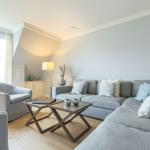 Wohnzimmer mit grauem Sofa, Couchtisch und Fenster.