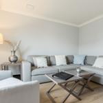 Wohnzimmer mit grauem Sofa, Couchtisch und Stehlampe.
