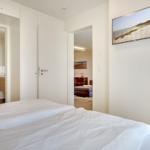Schlafzimmer mit Bett, Bad und Wohnbereich. Wandbild zeigt Strand.