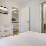 Schlafzimmer mit Bett, Schrank und TV. Blick in Küche und Bad.