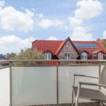 Terrasse mit Sitzgelegenheit und Blick auf ein Haus mit rotem Dach.