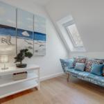 Dachgeschosszimmer mit Sofa, Fenster und Wandbildern