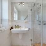 Badezimmer mit Dusche, Waschbecken und Fenster mit Handtüchern.