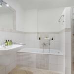 Badezimmer mit Badewanne, Dusche und Waschbecken mit Spiegel.