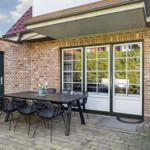 Terrace with table and chairs, glass doors and red roof