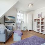 Living room with sofa, TV, and wooden furniture.